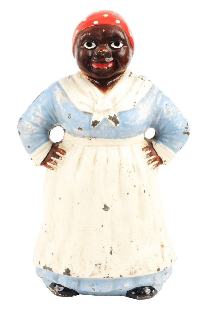Cast Iron Mammy w/ Hands on Hips Doorstop.: Made by Hubley. Depicts full-figure mammy with hands on hips wearing traditional apron and scarf. Blue dress paint variation. Book example. Condition:(Very Good).Dimensions:9" x 6".