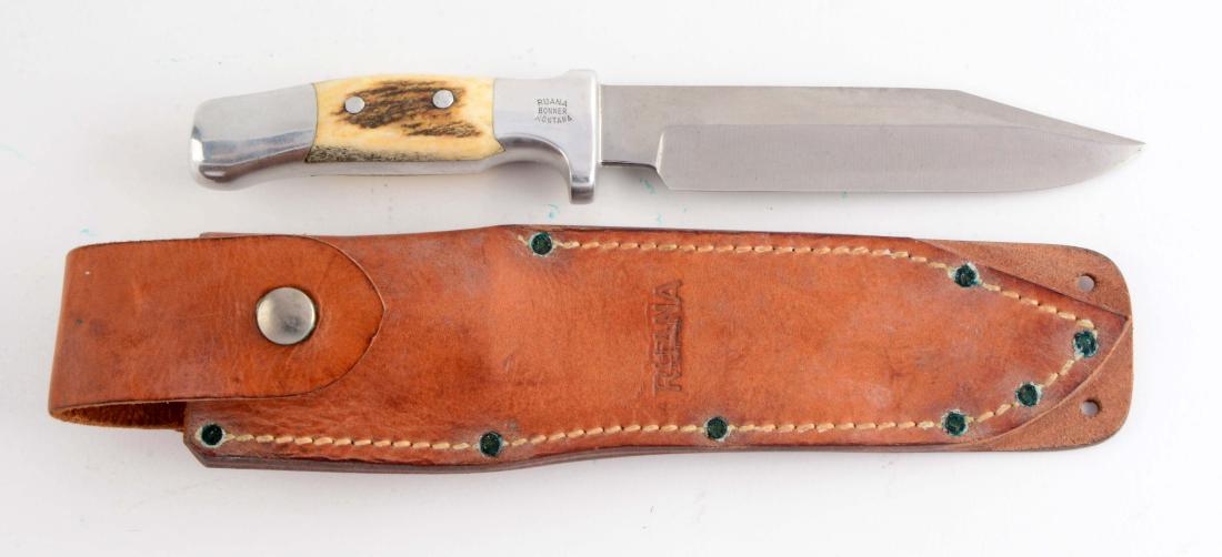 Ruana 25AC Stag Hunter: Saber ground spear point with sharpened false edge. Integral aluminum handle with full guard and full pommel, tapered stag inserts, guard marked "Ruana Bonner, Montana". Correct leather sheath. Circa 