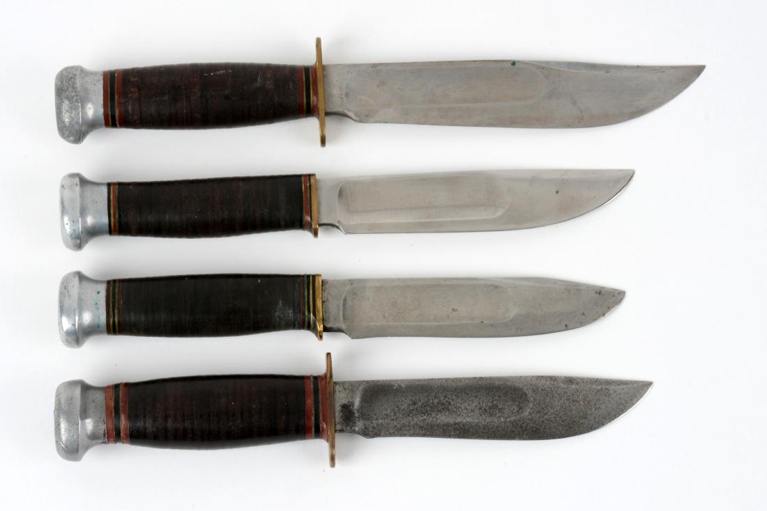 Lot of 4: Marbles Gladstone Mich. USA "Ideal" Fixed: Knife A) Clip point with fullers. Handled in stacked leather with aluminum crown and full brass guard. No sheath. Circa post 1942. Knife b) Clip point with fullers. Handled in stacked leather with alu