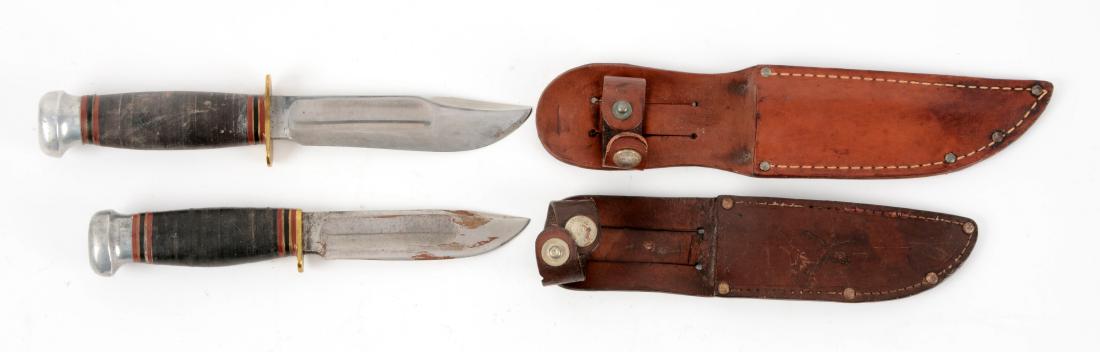 Lot of 2: Marbles Gladstone Mich. USA "Ideal" Sheath: Knife A) Clip point with fullers. Handled in stacked leather with aluminum crown and brass full guard. Non-original leather sheath. Circa post 1943. In very good condition. Knife B) Clip point with fu