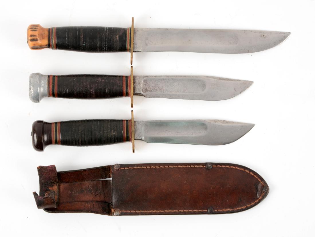 Lot of 3: Marbles Gladstone Mich. USA "Ideal" Sheath: Knife A) Clip point with fullers. Handled in stacked leather with stag crown and brass full guard. No sheath. Circa post 1943. In fair condition. Knife B) Clip point with fullers. Handled in stacked l