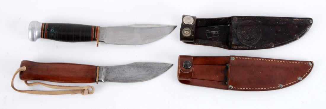 Lot of 2: Marbles Knifes with Sheaths.: Knife A) Woodcraft: Flat ground Skinner with thumb grooved back. Stacked leather handle with aluminum crown and brass half guard. Correct leather sheath with Boy Scouts of America logo, signed safety 