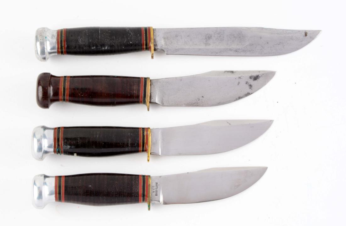 Lot of 4: Marbles Fixed Blades.: Knife A) Woodcraft knife: Skinner blade with thumb grooved back. Handled in stacked leather with a Bakelite crown and brass half guard. Knife B) Wood craft knife: Skinner blade with thumb grooved back
