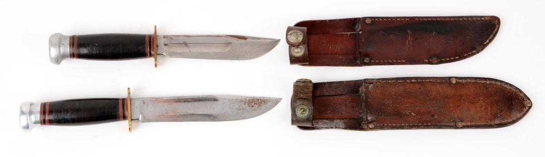 Lot of 2: Marbles Gladstone Mich. USA "Ideal" Fixed: Knife A) Clip point blade with fullers. Handled in stacked leather with aluminum crown and brass full guard. Correct sheath with signed safety snap. Circa post 1943. Knife B)Clip point blade with full