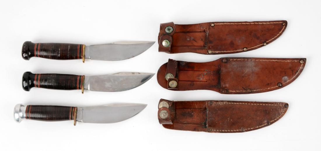 Lot of 3: Marbles Gladstone Mich. USA "Woodcraft" Fixed: Knife A) Blade with thumb grooved back. Handled in stacked leather with lignum vitae crown and brass half guard. Incorrect sheath. Circa pre-1943. In near mint condition. Knife B) Blade with thumb gro