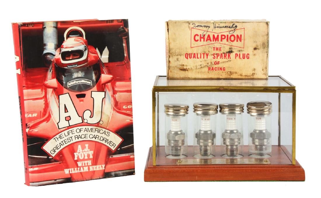 Tommy Hinnershitz Spark Plugs in Case with Book.: Four spark plugs in a nice glass display case with a signature of Tommy Hinnershitz and a book titled "A.J. The Life of America's Greatest Race Car Driver" where AJ Foyt talks about Tommy. Condition: 