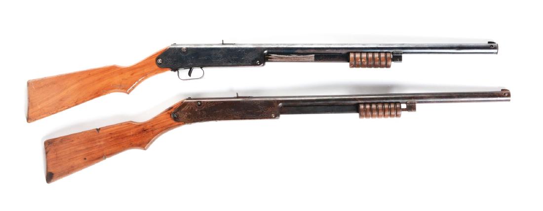 Lot of 2: Daisy Model 107 Buck Jones Special Air: Both have slide action, blue finish, sundial markings on wooden stock, needle or floating compass, Daisy marked on compass dial, 60 shot gravity-fed magazine, six groove slide handle. Manufactured 193