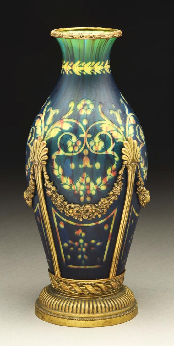 Abel Combe Intaglio Carved Vase.: Intaglio carved vase has blue glass exterior over a vertically striped glass interior of yellow and red. The vase is intaglio carved with scrolls and garlands surrounding the shoulder along with four 