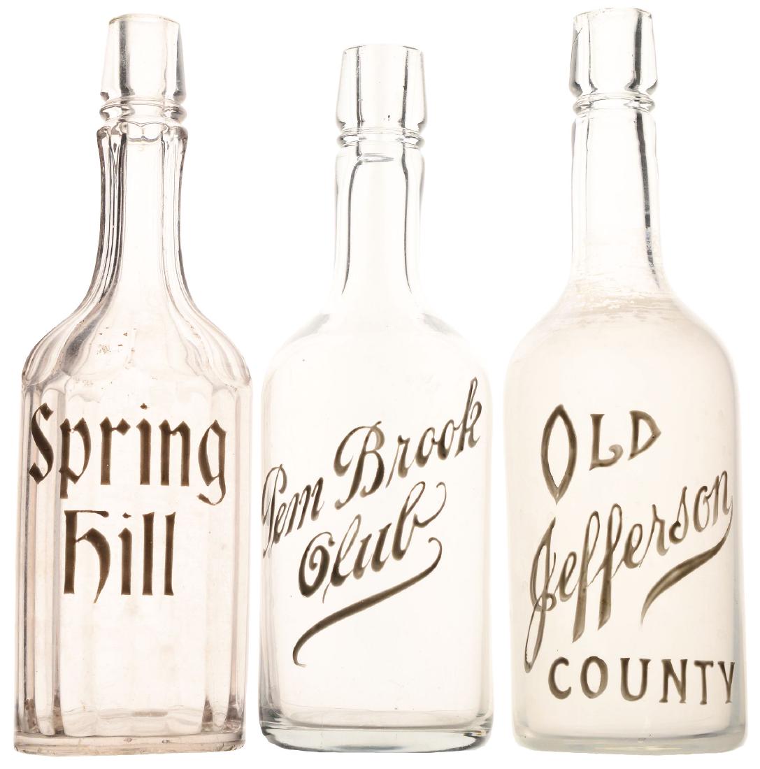 Lot Of 3: Early Glass Whiskey Bottles.: This lot of three includes 1- beveled glass whiskey bottle with "Spring Hill" enameled in white. 12"T x 3-1/2" Dia.; 1- frosted glass whiskey bottle with "Old Jefferson County" enameled in white. 11-1