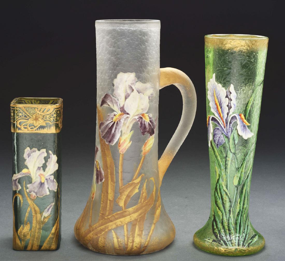 Three Mont Joye Pieces.: Lot consists of a tankard, a round vase and a square vase. The three Mont Joye pieces are each enameled with large iris flowers in white, lavender and yellow. The square vase is signed on the undersid