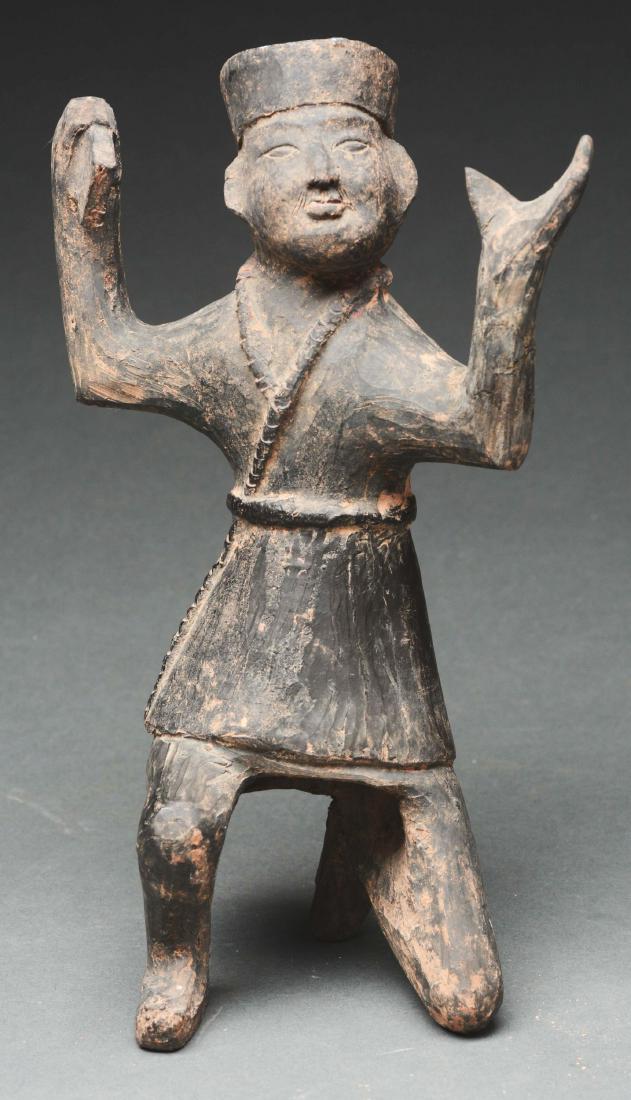 Terra Cotta Boy Dressed as a Cossack Dancer. Wei: 386 - 581 A.D. Wei Dynasty. China. The figure dressed in a belted coat in the fashion of a Cossack dancer. The boy is dancing with one knee down and arms outstretched with an object in his right hand.