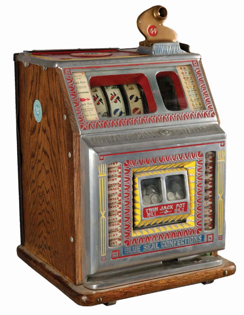 **5¢ Watling Blue Seal Confections Twin Jackpot Slot: A three reel slot machine with two jackpot banks flanked by mint vendor columns. The cast aluminum front panel shows an older restoration, detailed in colors of blue, yellow and red. Retaining the ori