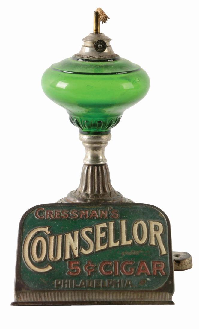 Cressman's Counsellor Cigar Lighter & Lamp.: This very ornate lighter has an embossed and painted design on the front. Missing the top globe. There is oxidation and soiling on the base and some paint loss to the front design. Condition: (Very Go