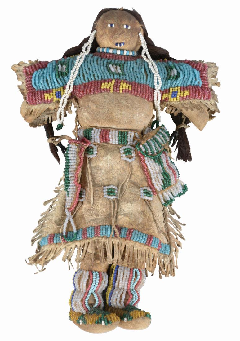 Sioux Female Doll.: Circa 1880's, made of Indian tanned buckskin and human hair. Entirely sinew sewn fringed dress with buffalo hair, beaded yoke, belt, knife and pouch and high top moccasins. Beadwork is executed in gre