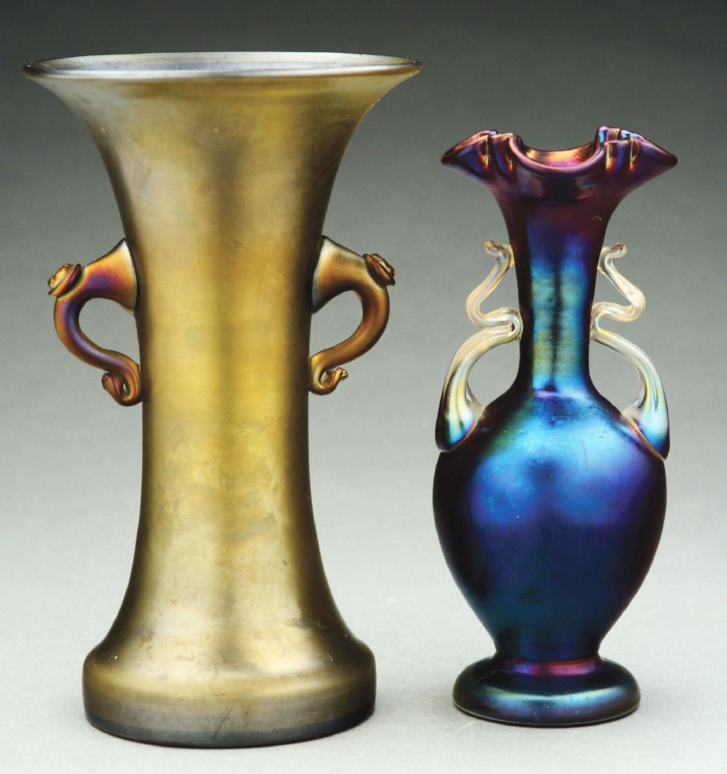 Two Loetz Art Glass Vases.: 1) Loetz bronze Glatt vase has flaring lip and is finished with two applied prunt handles. Unsigned. 2) Loetz Rubin Matte Iris handled vase has rich purple iridescent finish and is completed with appl