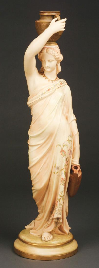 Fine Royal Worcester Figure of a Female Water Carrier.: The figure in blush ivory porcelain holding a two-handled urn upon her head, an amphora held in her right hand, dressed in flowing robes highlighted with enameled floral and vine decoration and mounte