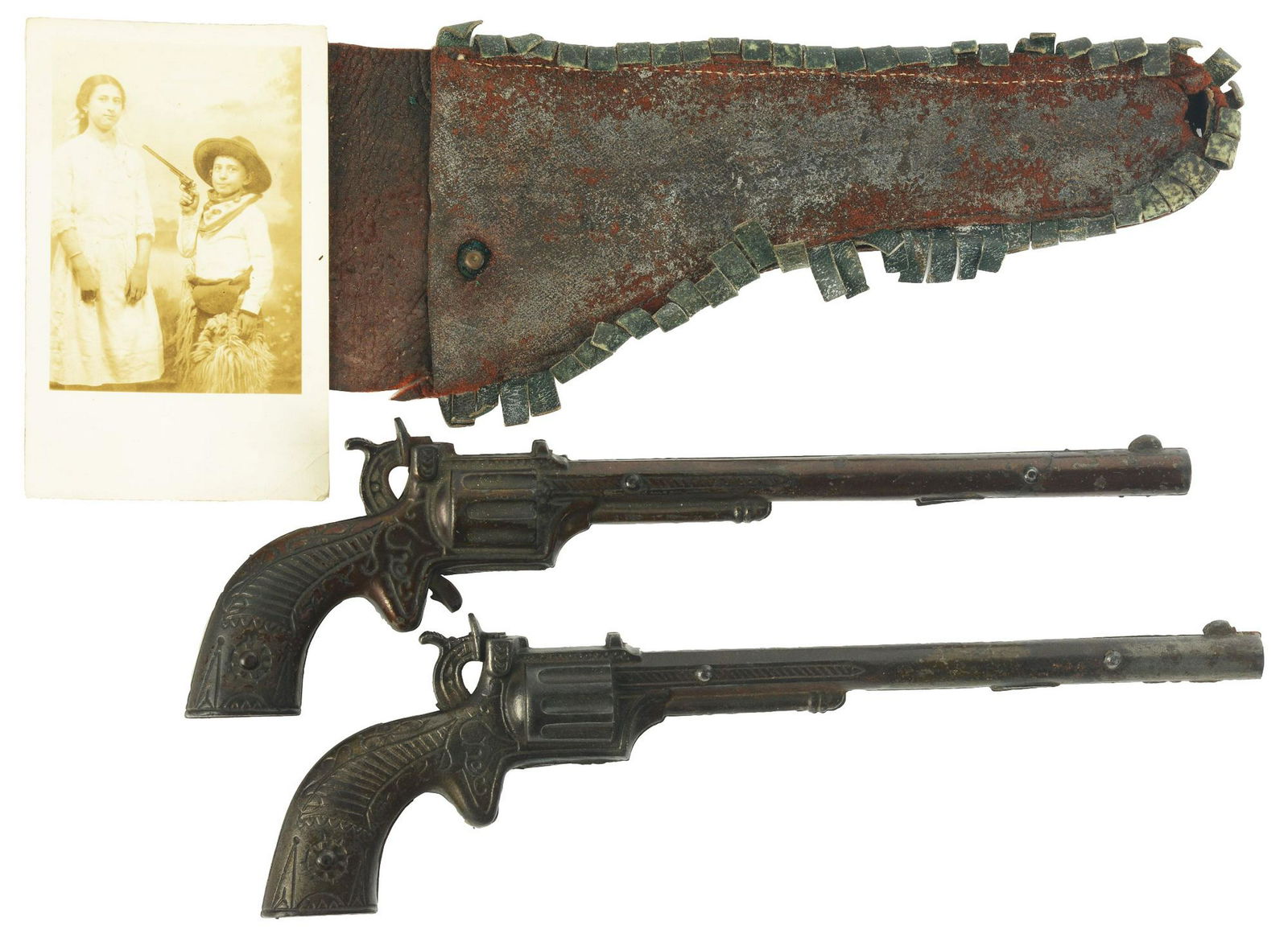 Lot of 2: Buffalo Bill Cap Pistols with Holster &: One is circa 1890 and has nice japanning, the second is circa 1916. Comes with leather holster and photograph postcard of boy pointing similar cap gun at presumably sister. Interesting lot. Condition: