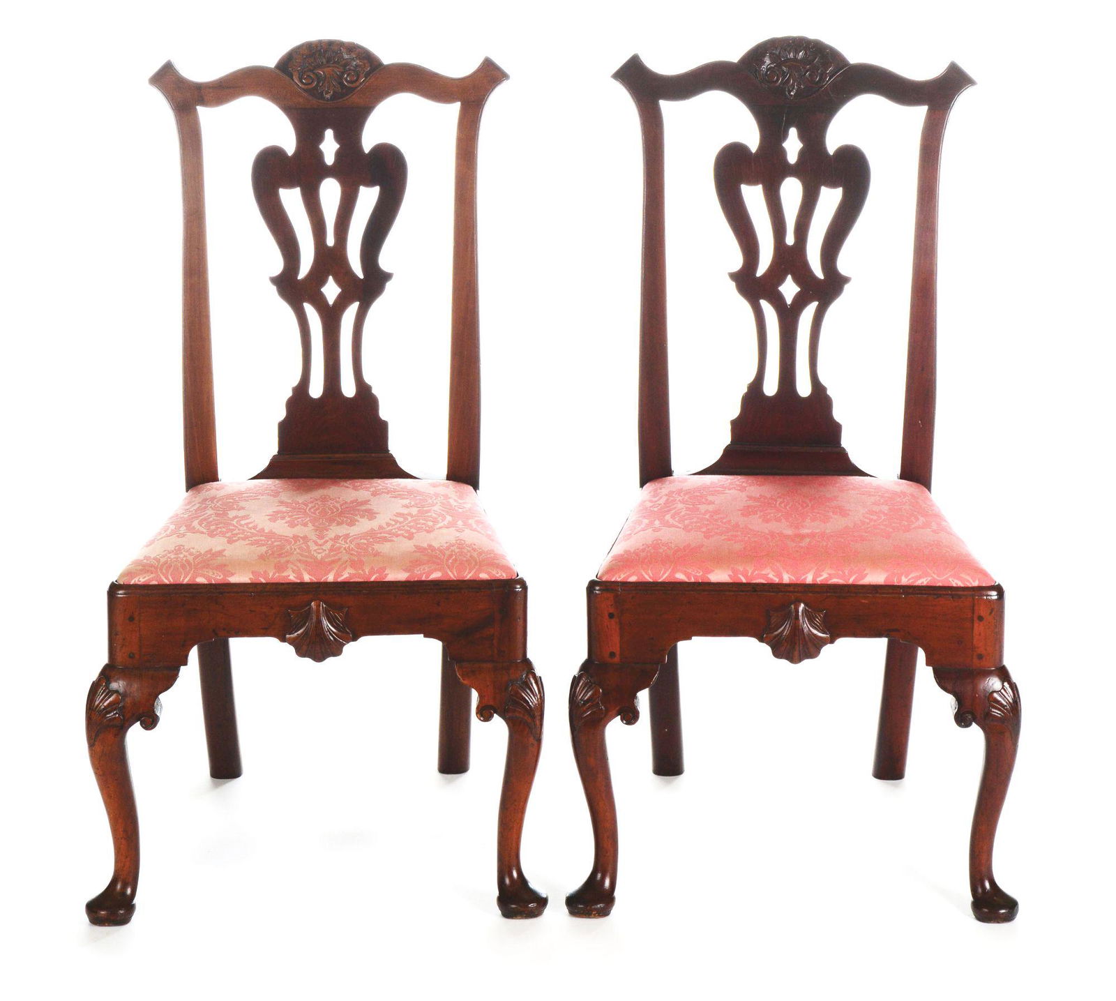 PAIR OF CHIPPENDALE SIDE CHAIRS. PHILADELPHIA,: An eared crest rail of early form with a carved oval shell of fully developed type. A broad vertically pierced splat with boldly molded seat rails supports a slip seat. The front rail is enhanced with