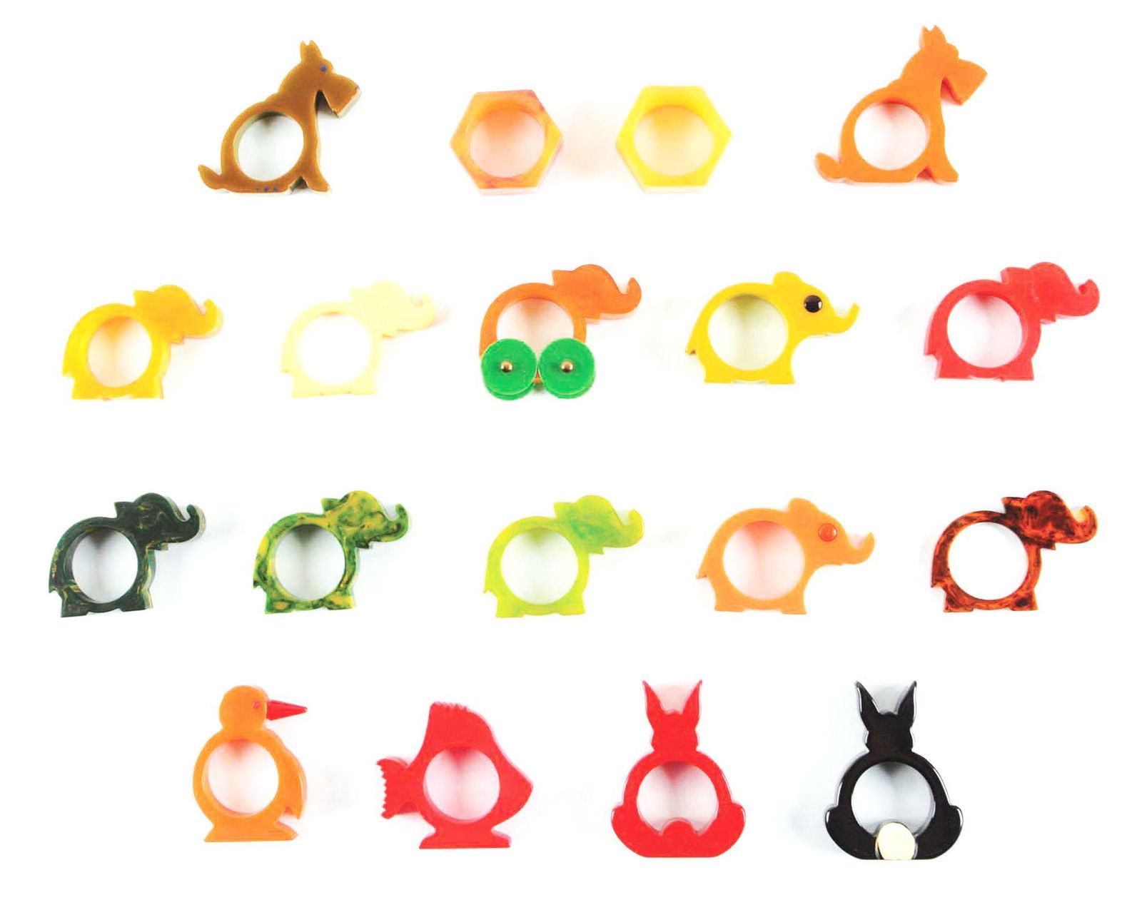 LOT OF 18: BAKELITE ANIMAL FIGURE NAPKIN RINGS.: Lot includes 10 elephants: 2 with eyes, one with wheels; 2 standing rabbits, 2 Scottie dogs, a bird, a fish and 2 hexagonal rings, all in excellent condition and 2 - 1/2" tall. Condition: (Excellent).