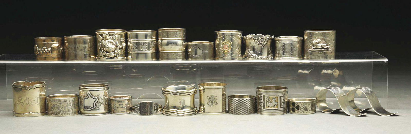 LOT OF 22: STERLING SILVER NAPKIN RINGS.: c. 1870 - 1971. Lot includes two matching 1971, a 1904 Scottish, an 1875 Scottish, a 1900 R.A.J., an 1875 coin with gold, an 1878 coin with gold, an 1880 coin, a Gorham with wave edge, a Gorham with P