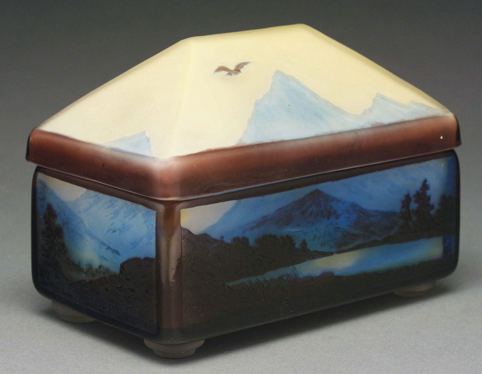 GALLE CAMEO COVERED BOX.: Galle scenic box has a cameo scene on each side panel showing brown cameo trees and land with blue cameo mountains in the background. The scenes on the front and back includes a blue lake. The box is