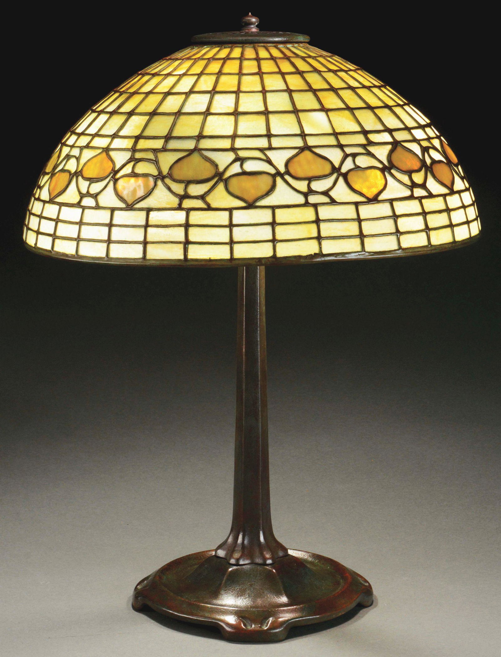 TIFFANY STUDIOS ACORN TABLE LAMP.: Tiffany Studios table lamp has leaded glass shade in the Acorn pattern with a single band of acorns surrounding the side of the shade. The acorns are done in amber glass against a light amber backgrou