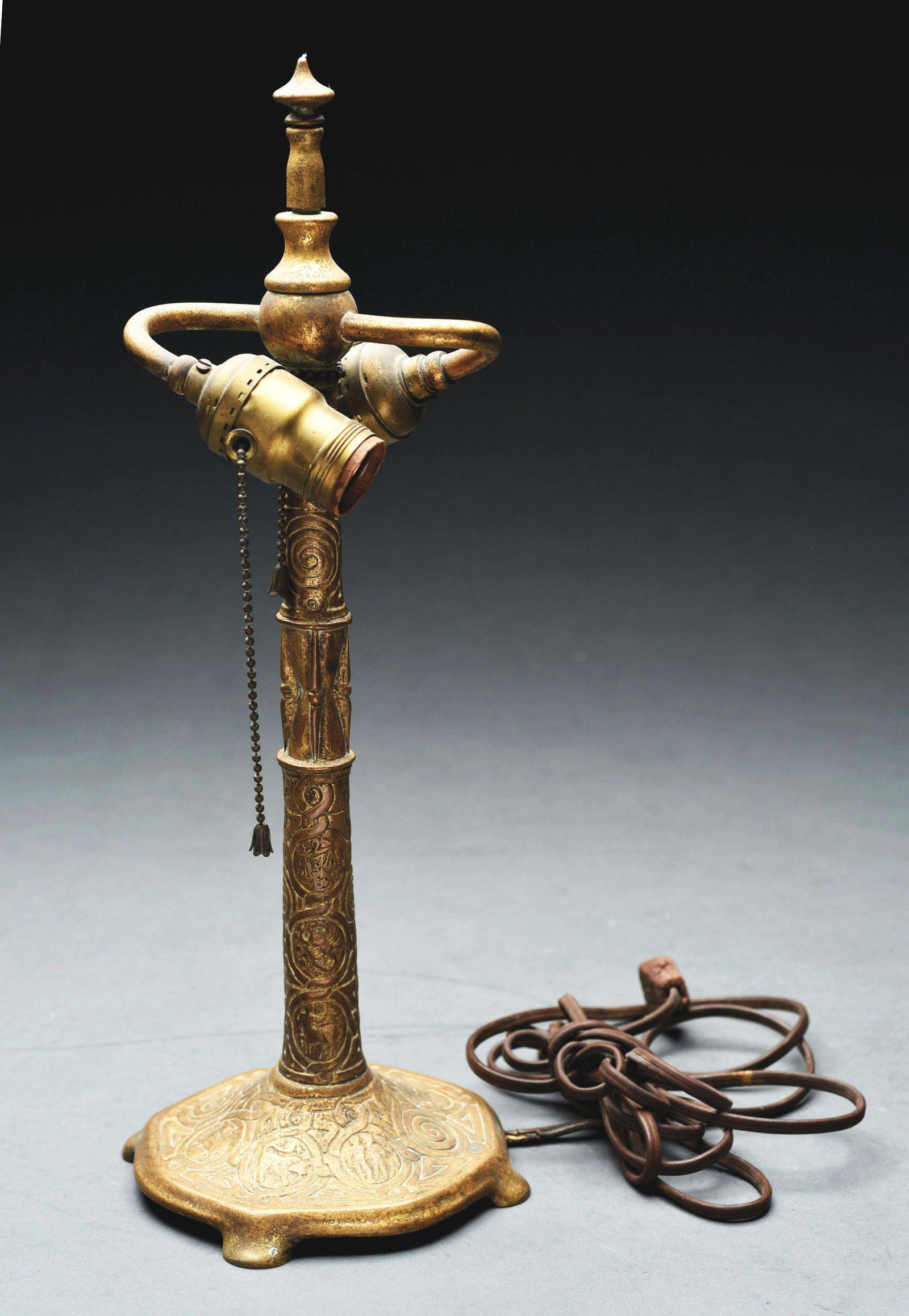TIFFANY STUDIOS ZODIAC LAMP BASE.: Base has raised scrolling decoration with medallions depicting signs of the Zodiac. Mottled gilt finish. Base stamped "Tiffany Studios New York 537". Condition: (Excellent). Dimensions: 17" x 6 - 1/2"