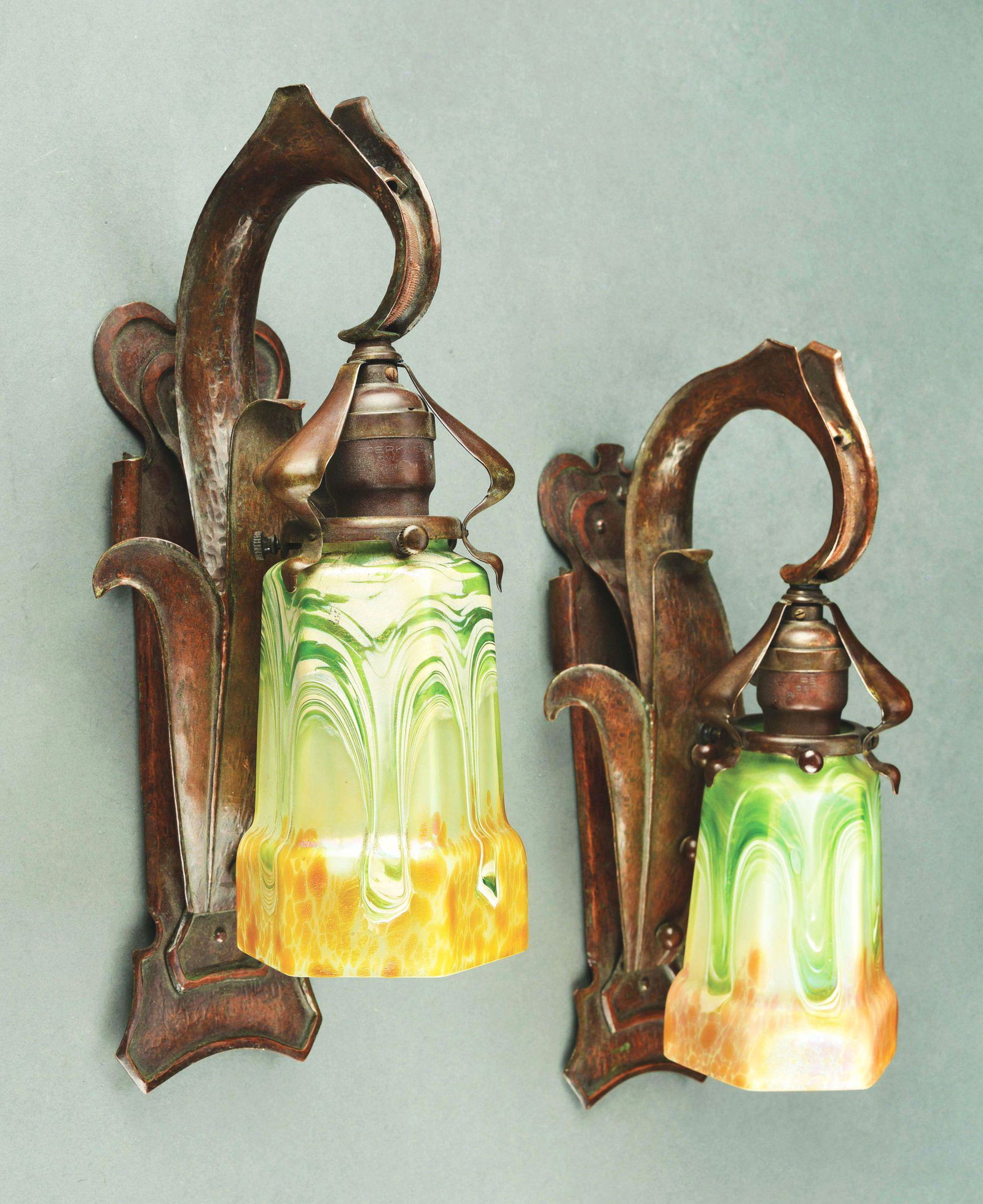 PAIR OF LOETZ AUSTRIAN ART NOUVEAU HAMMERED SCONCES.: A pair of Loetz Austrian Art Nouveau hammered copper sconces each decorated with matching Loetz decorated shades. The sconces are hammered copper with a very heavily stylized fleur-de-lis motif. Condi