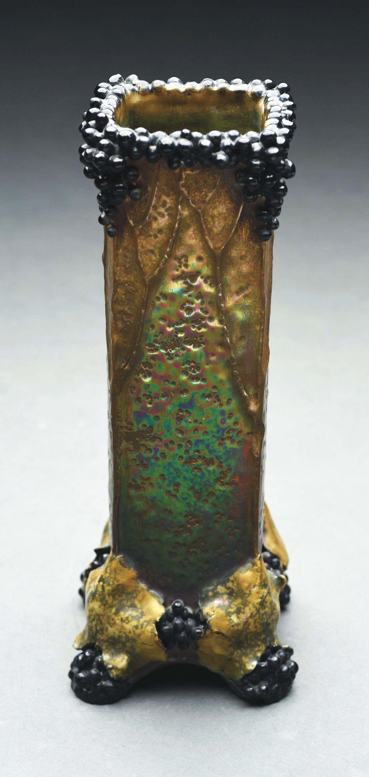 AMPHORA CURRANT VASE.: Gold and reddish iridized body with applied black currants on the base and rim. Marks glazed over on the underside. 9" tall. A similar example is illustrated in "The House of Amphora", Scott, page 144