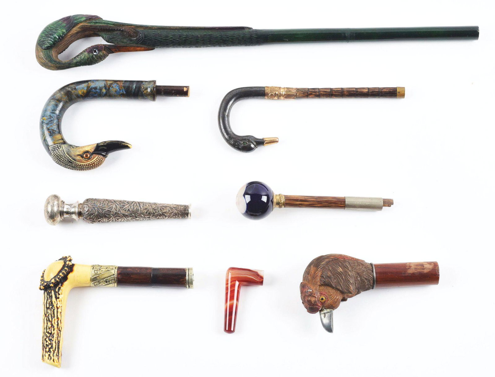 LOT OF 8: VICTORIAN UMBRELLA HANDLES.: Lot consists of eight umbrella handles. Four carved wood in form of birds with glass eyes, one of antler with carved dog, one glass with enamel of lady, one of Asian silver, and one of marbleized glas