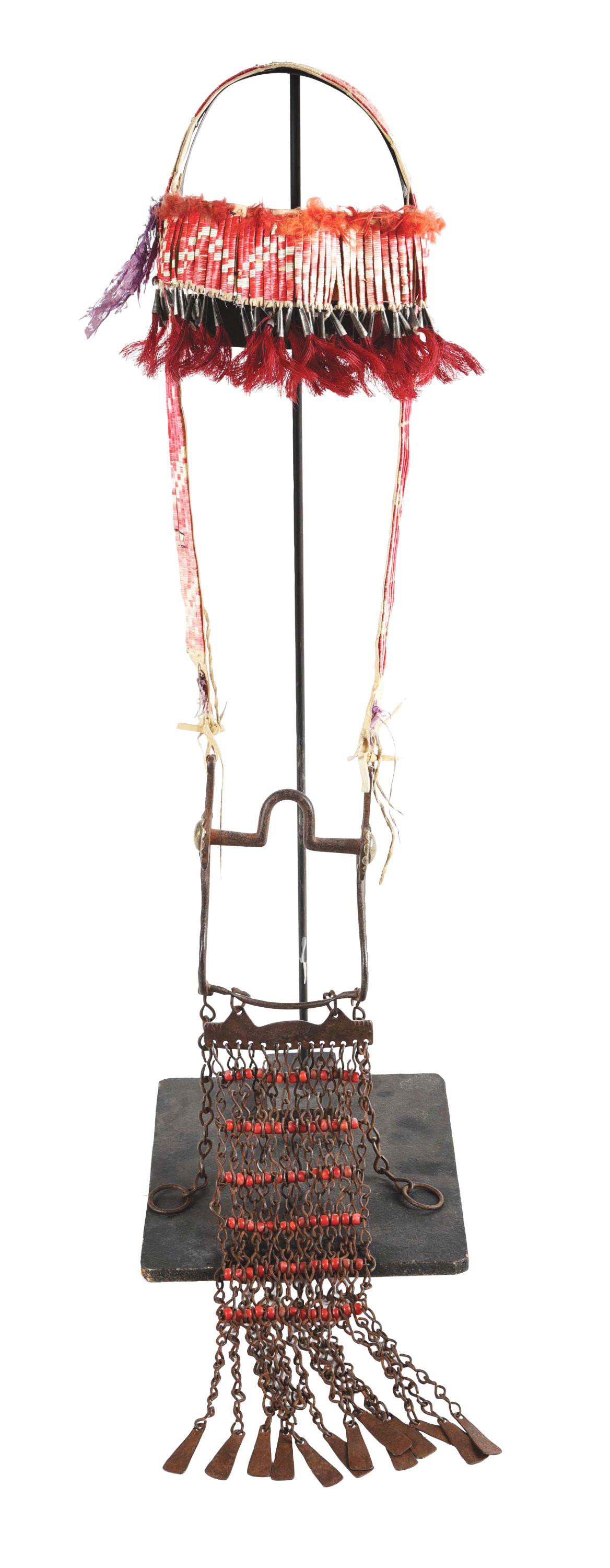 QUILLWORK BRIDLE WITH CONVERTED US BIT.: Quillwork on brain tanned hide bridle with geometric designs of red, pink and white. Silver bells with red horsehair on the brow band. US curved bit that has been converted with two silver conchos ins
