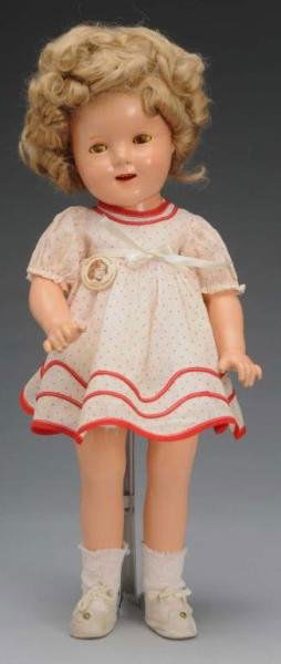 Ideal Composition Shirley Temple Doll: Description American, 1930s. Embossed "Shirley Temple" on head and body with original curly mohair wig, splattered eyes with perfect eyelashes, and dimples. Wearing original dress with reproduction bu