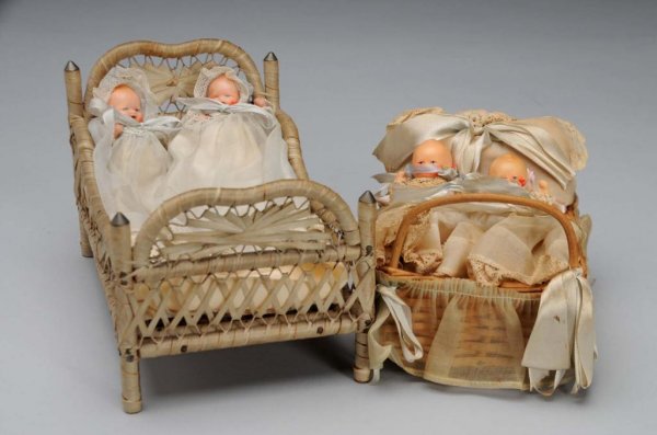 Lot of 2: Doll Beds with Painted Bisque Babies.: Circa 1940s. One set has painted bisque babies incised Made in Japan, jointed shoulders and hips, open mouths, original organdy baby dresses, matching hats, diapers and booties, in a cute wicker bed w