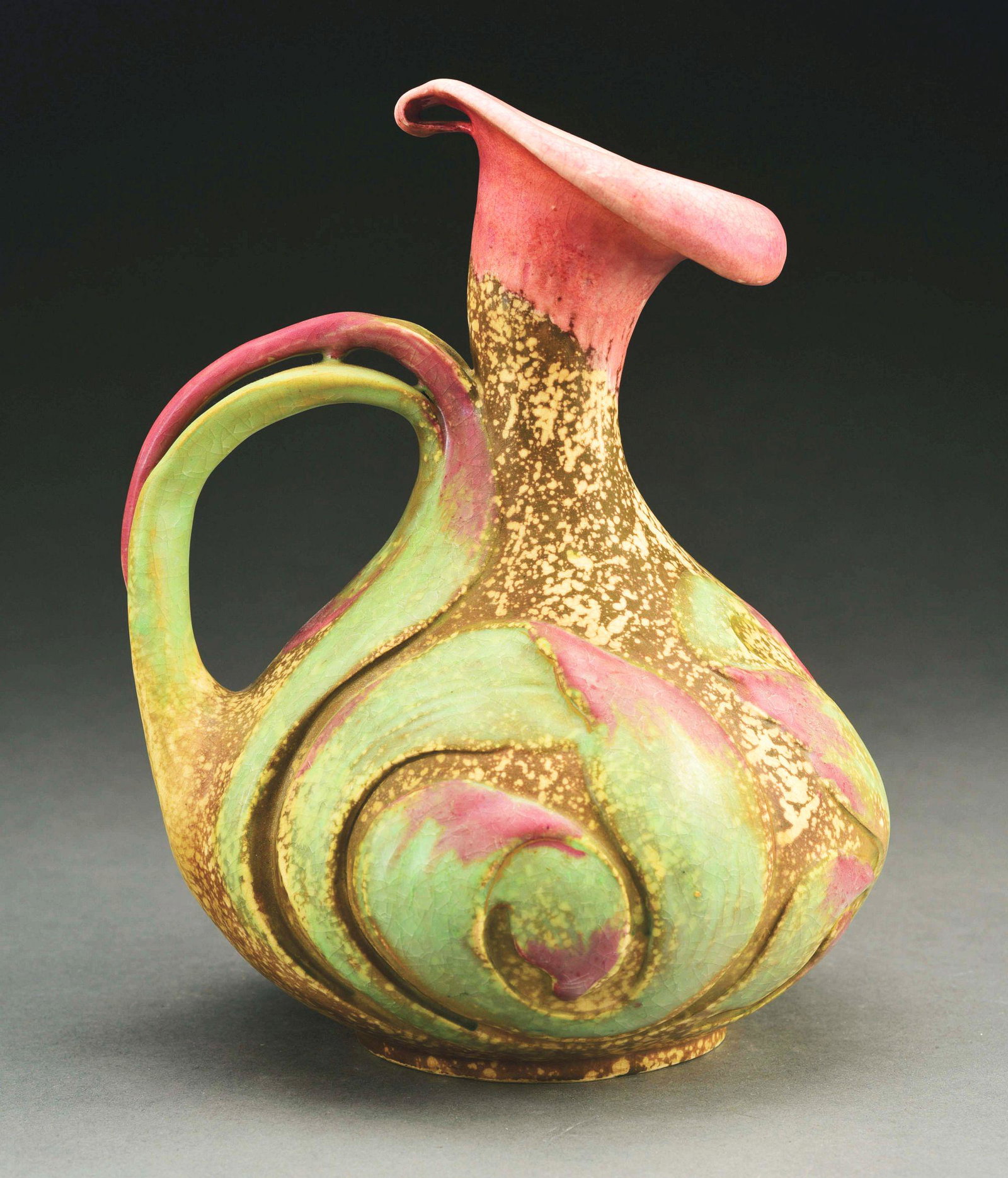 AMPHORA CALLA LILY PITCHER.: Pink, green and beige glazes. Crown mark, Amphora Oval mark, impressed "362-4". 10" high. Illustrated in Monsters and Maidens: Collectors Edition, Vreeland, p. 195. Condition: (Mint). Dimensions: 10" 