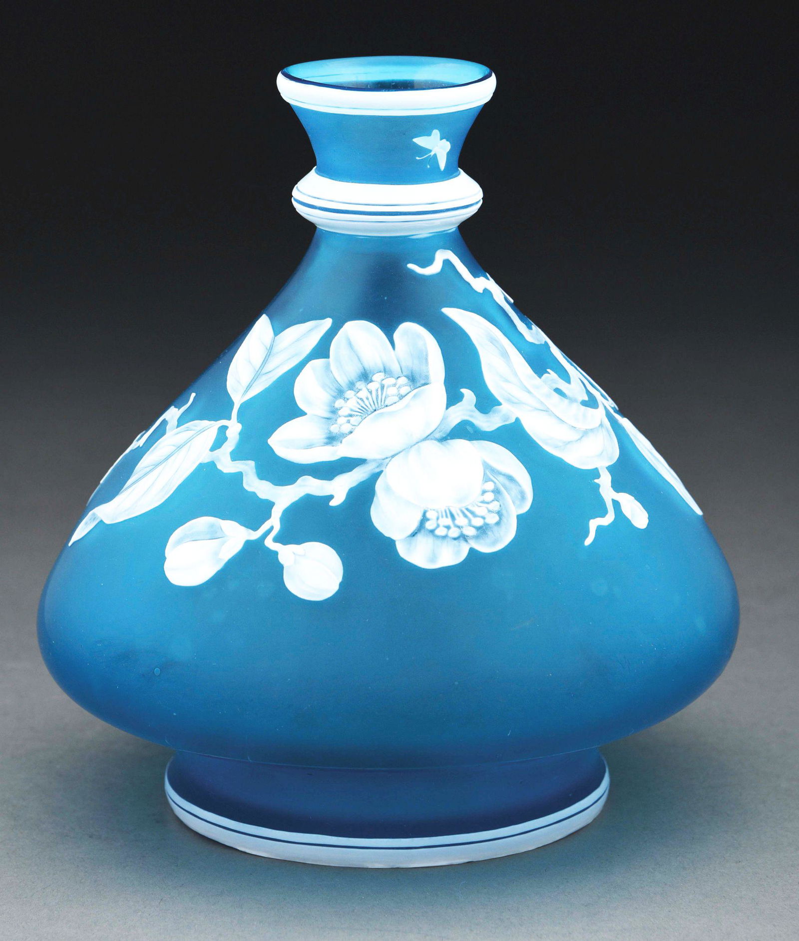 WEBB BLUE FLORAL VASE.: Beautiful cameo pedestal vase by Thomas Webb and Sons. Depicting a clematis blossom and butterflies in white, set against a Prussian blue ground. Measures 7” tall by approximately 7” across at its