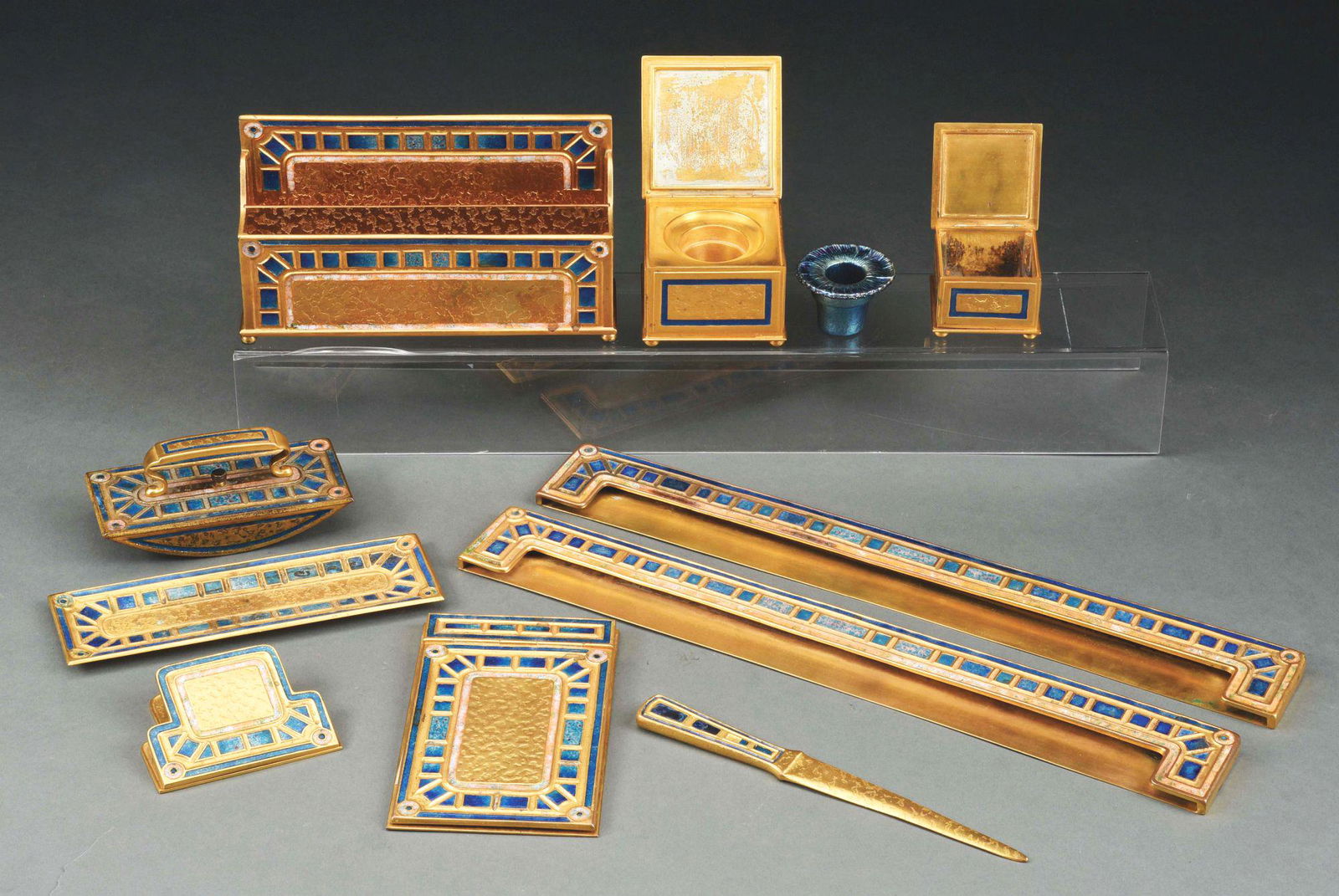 ENAMELED ART DECO PATTERN DESK SET.: Tifffany Furnaces enameled and bronze blue Art Deco pattern desk set consisting of a letter rack, pen holder, letter opener, memo pad, paper clip, rocker blotter, blotter ends, an inkwell decorated wi