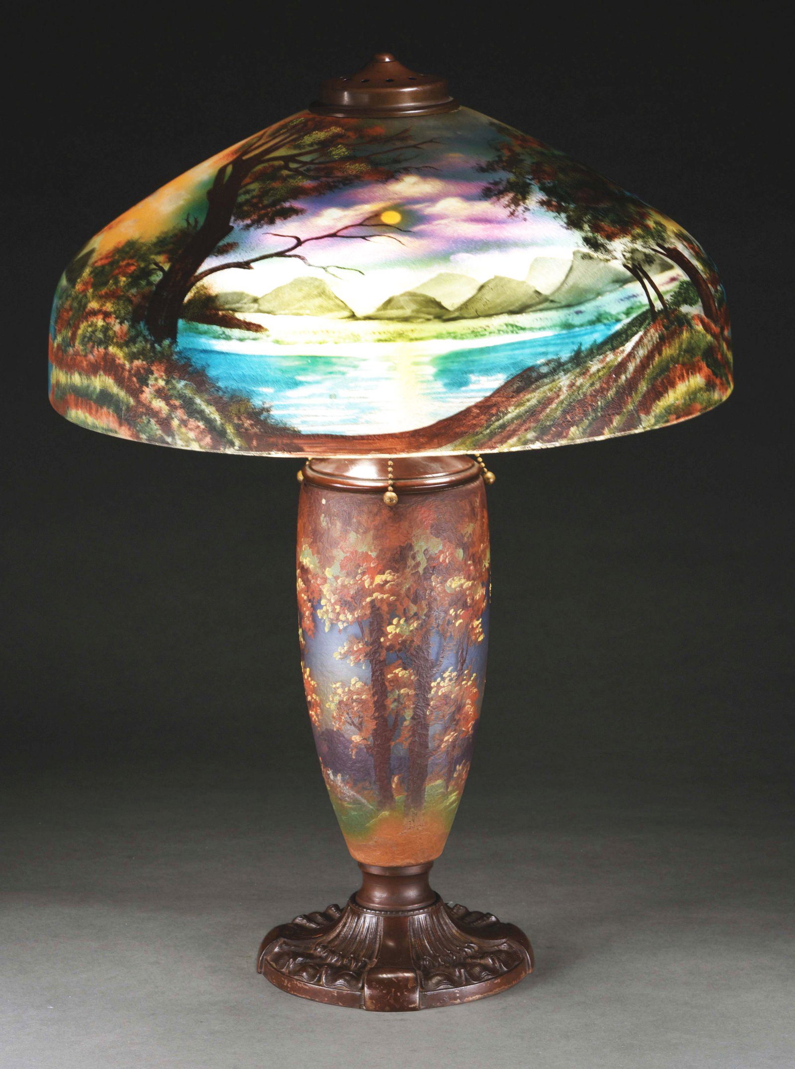 PITTSBURGH REVERSE AND OBVERSE PAINTED LAMP.: A beautiful and rare painted lamp by Pittsburgh. The shade is reverse painted, depicting a woodland scene at night. The trees are set against a night sky of gorgeous blues and purples with an eerie ye