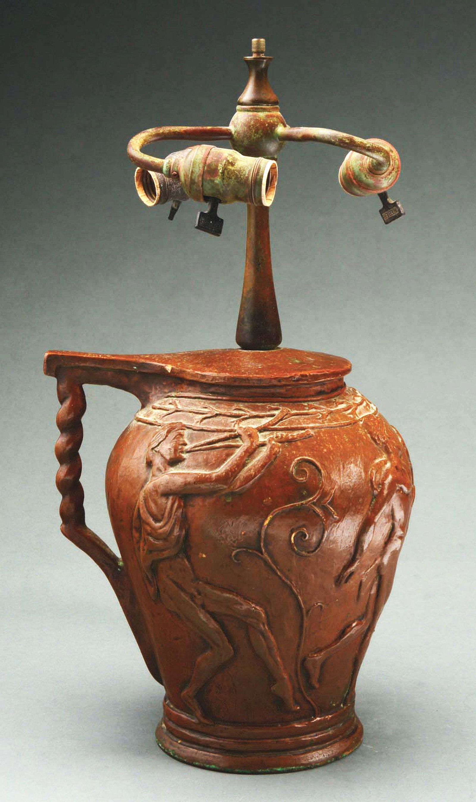 TIFFANY BRONZE POTTERY LAMP BASE.: Tiffany bronze pottery lamp base is decorated with four nude men, one carrying a basket of flowers, two of them playing a flute, and the fourth carrying a scepter. The base is further decorated with s