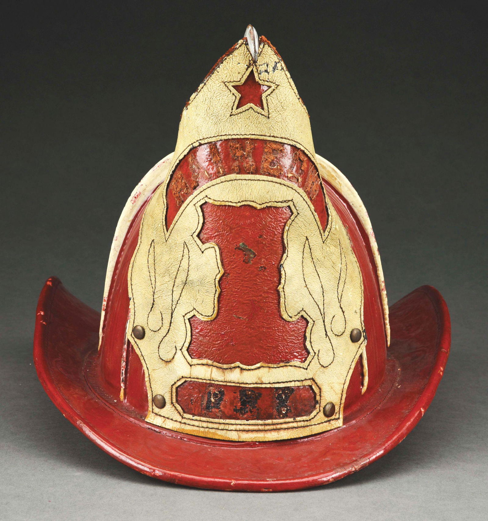 RAINBOW NO. 1 FIRE HELMET.: Red painted leather four-comb fire helmet circa 1880's from Schuylkill Haven, Pennsylvania. With a pressed brass high eagle and applied cut leather shield with sewn details. Dated 1773 on brim. Missin