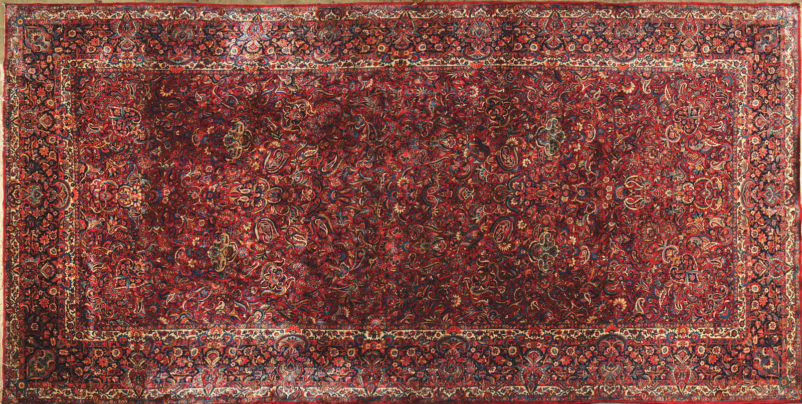 EXQUISITE KASHAN ORIENTAL CARPET.: Early 20th century. Woven with an overall arrangement of floral arabesque design in rich shades of red, ivory, indigo and pale turquoise blue on a deep burgundy red field. All within a floral filled a