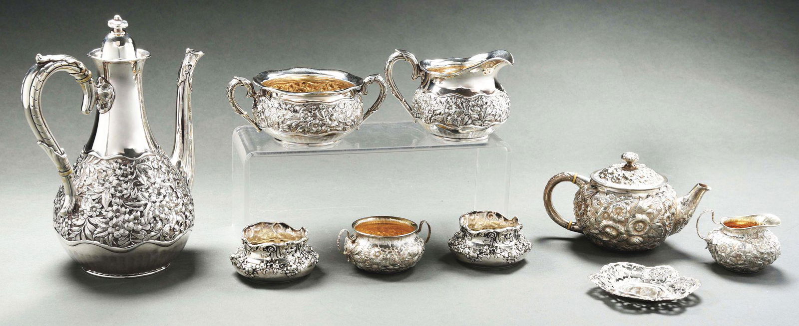 AN AMERICAN STERLING THREE-PIECE COFFEE SET.: Theodore Starr, the coffee pot with a tapering plain neck and the cream jug and sugar bowl chased with a broad band of scrolling foliage and flower heads, the cream and sugar also with the mark of Dom