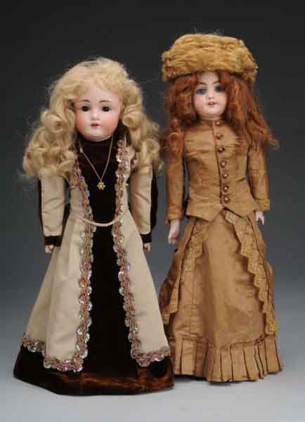 Lot of 2: German Bisque Shoulder Head Dolls.: Description Largest doll is a Simon & Halbig doll with blue glass sleep eyes, leather body, bisque forearms, and elegantly dressed in a silk fashion doll costume. Also includes a Kestner 154 shoulder
