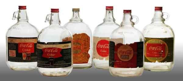 Lot of 6: Coca-Cola 1-Gallon Syrup Jugs.: Description 1930s to 1960s. Each jug includes a paper label with general overall light to heavy wear. Condition (6.0 - 8.5, Good - Excellent). Size 12".