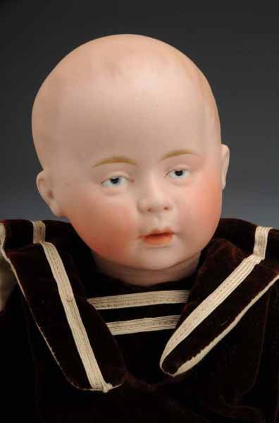 Swaine & Co. Character Baby Doll: Description Germany, Ca. 1910. Bisque socket head incised "D1" with round green S & Co. stamp. Molded and painted hair, intaglio eyes, molded eyelids, closed mouth. Composition baby body (repainted).