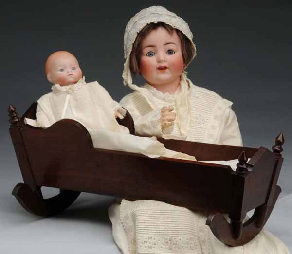 Lot of 2: Character Babies.: Description Germany, Ca. 1925. Bisque head baby incised "1925", probably Recknagle, new cloth body with bisque hands, lovely old vintage baby clothes, in an antique wood cradle with original bed linen