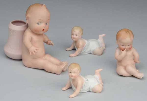 Lot of 4: Gebr. Heubach Figurines.: Description Germany, Ca. 1915. Sitting boy with Square Mark attached vase (two fingers chipped). Sitting boy with finger to mouth (glued at neck), Two crawling babies (both glued at shoulder). Conditi