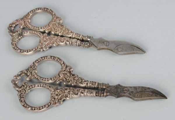Lot of 2: Pairs of Silver Unger Brothers Scissors: Description Each pair with an ornate handle chased with beads, scrolls, and flowers. Company trademark is on steel blades. Condition (Very Good). Size Both: 6" L.