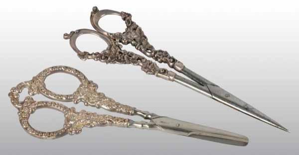 Lot of 2: Pairs of Silver Handled Scissors.: Description Each pair chased with beads, scrolls, and flowers. One pair by Unger Brothers. Condition (Very Good). Size Largest: 7" L.