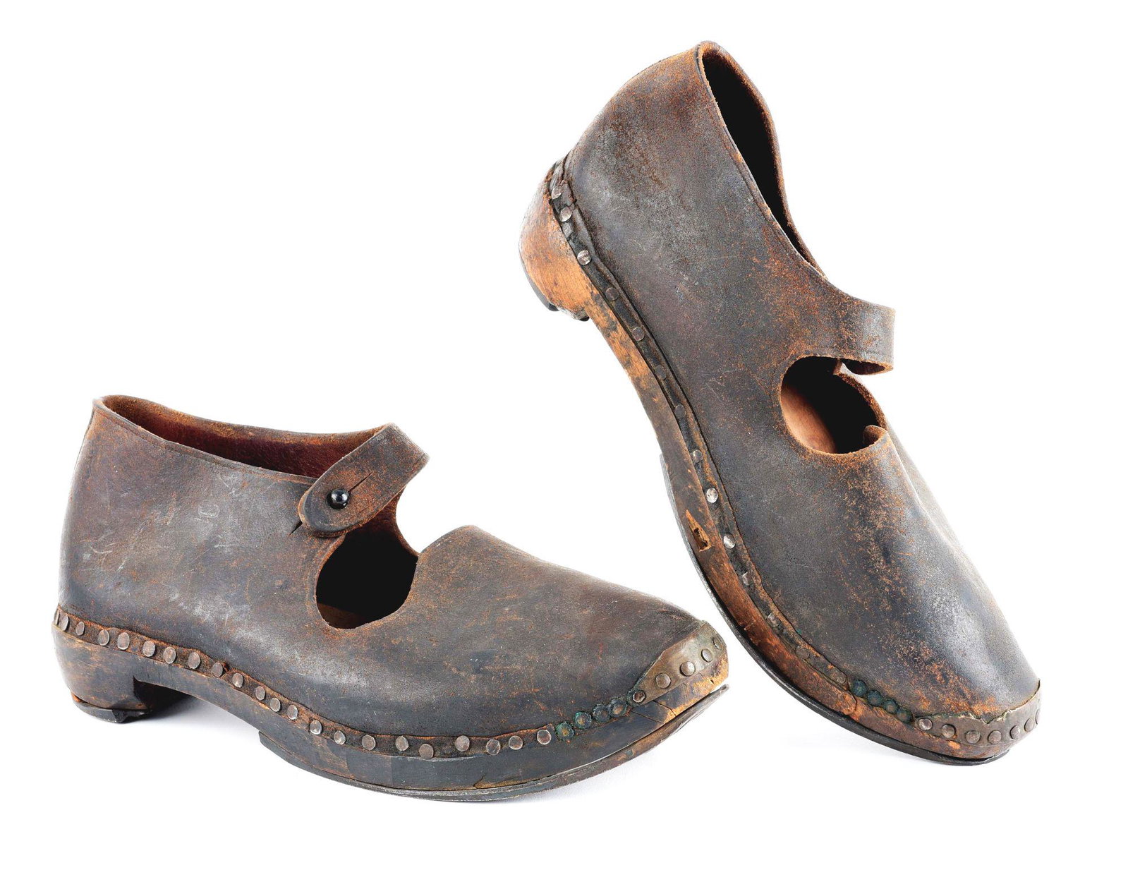PAIR OF WOOD AND LEATHER SLAVE SHOES: The shoes are constructed of a hand carved wooden sole with iron plates reinforcing the heel, sole, and toe which are attached to the shoes by nails. The upper portion of the shoes are constructed wit