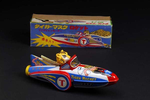 Tiger Mask Rocket Toy.: Description Japanese. Made by Masudaya. Working. When in operation, toy rolls forward via friction motor while emitting a plinking sound. Includes original box with some fading and wear throughout. Co